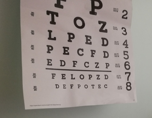 Sehtesttafel mit Buchstaben in verschiedenen Größen, von groß oben bis klein unten, mit Zahlen rechts und links zur Messung der Sehschärfe.