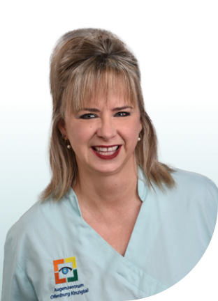 Frau mit hochgestecktem blonden Haar trägt hellblaue Arbeitskleidung mit Logo des Augenzentrums auf der Brust.