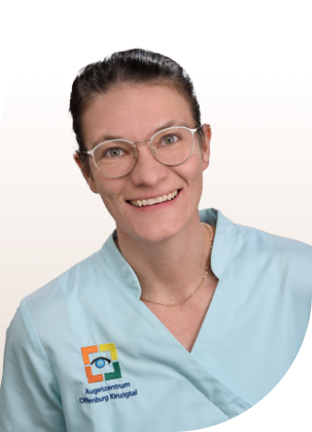 Person trägt hellblaue medizinische Arbeitskleidung mit Logo und Schriftzug 'Augenzentrum Offenburg Kinzigtal' auf der Brust.